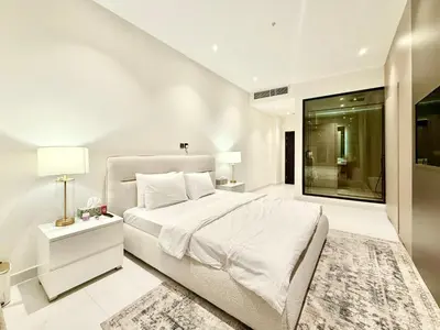 a white bedroom with a large bed and a window at Luxury Studio Apartment Near Jumeirah Beach in Dubai