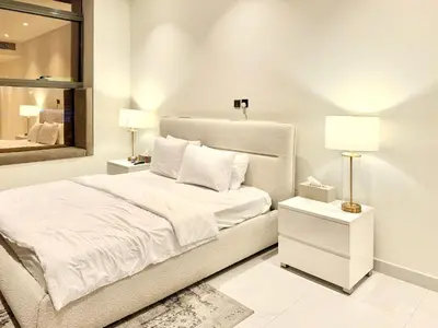 a white bedroom with a bed and a mirror at Luxury Studio Apartment Near Jumeirah Beach in Dubai