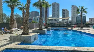 a swimming pool with palm trees in a city at Sparkle Tower by Swarovski, Premium Full Marina View, 2min JBR & Metro, Sleeps 4 in Dubai