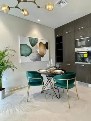 a dining room with a table and two green chairs at Fully furnished studio with amenities in Dubai in Dubai