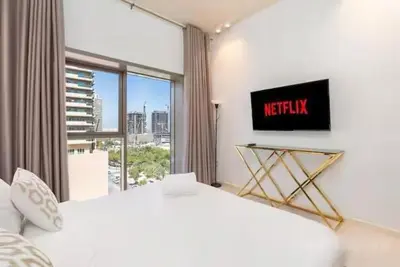 a bedroom with a white bed and a large window at Fully furnished studio with amenities in Dubai in Dubai