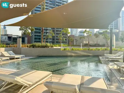 a swimming pool with chairs and an umbrella at HiGuests - High Rise Studio Haven in Business Bay in Dubai