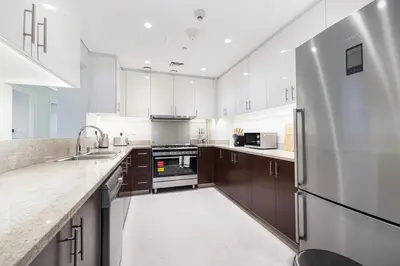 a kitchen with white cabinets and a stainless steel refrigerator at Spacious Lux 4 Bed with Large Balcony and Burj View by Vista Stays Dubai in Dubai