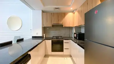 a kitchen with wooden cabinets and a stainless steel refrigerator at 1BR Study luxury Furnished Utilities Included DXB in Dubai