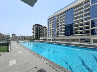a large swimming pool in front of some buildings at Vogue Dubai Hills The Pinnacle near Dubai Hills Mall and Park, One Bedroom Apartment with Large Balcony and City View, Access to all Amenities in Dubai
