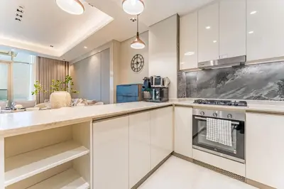 a kitchen with white cabinets and a stove at Sky-High 2BR with City Views, Minutes Drive to Downtown, Steps from the Bus Stop, Nobles Tower, Business Bay by Deluxe Holiday Homes in Dubai