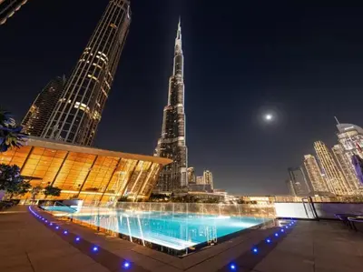 a building with a fountain in front of a city at night at Grande-5703,2 BHK Down Town, Dubai in Dubai