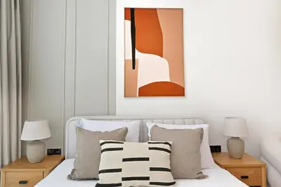 a bedroom with a bed with pillows and a painting at Aura by Grovy Studio - Parking, Sauna&Gym, Pool - by Rentujemy in Dubai