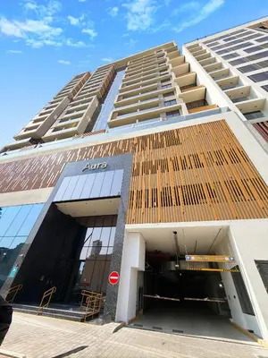 a large apartment building with an sign on it at Aura by Grovy Studio - Parking, Sauna&Gym, Pool - by Rentujemy in Dubai