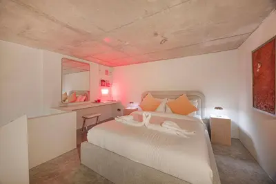 a bedroom with a large white bed with orange pillows at Stylish Studio Loft with Outdoor Patio in JVC in Dubai