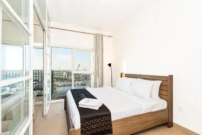 a bedroom with a bed and a large window at Escape24 Contemporary 1BR with City Views in Dubai Hills in Dubai