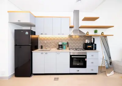 a kitchen with white cabinets and a black refrigerator at Escape24 Contemporary 1BR with City Views in Dubai Hills in Dubai