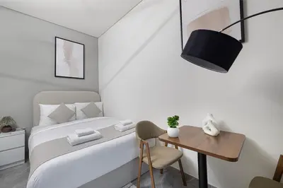 a small bedroom with a bed and a wooden table at Brand New Building! 2 Double Bed! Ideal Location with 5-star Pool and Gym! in Dubai