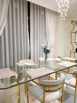 a glass table with white chairs and a vase of flowers at Smile Home Marina JBR Bed space in Dubai