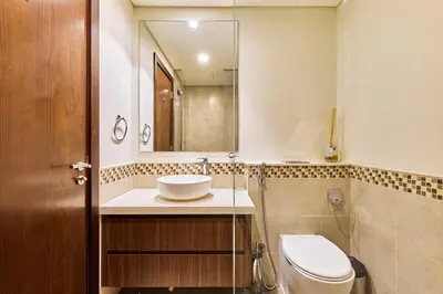 a bathroom with a toilet and a sink and a mirror at Modern 2BR Retreat Canal Views Near Downtown in Dubai