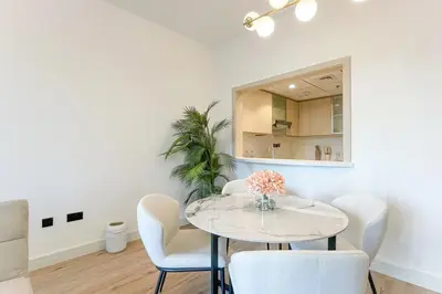 a dining room with a white table and chairs at Elite LUX Holiday Homes - Cozy City Escape in Standpoint Downtown in Dubai