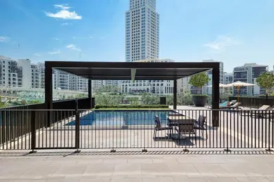 a pavilion with a table and chairs next to a pool at Creek Escape - Palace Residences - Creek Harbour in Dubai