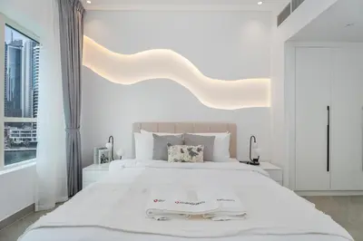 a white bedroom with a large bed with two towels on it at Gala Guests - Marina Views Bright Balcony Collection in Dubai