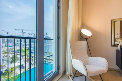 a living room with a white chair and a large window at Cozy 3BR Sea-View Apartment in La Rive 1 in Dubai