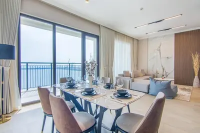 a dining room with a table and chairs and a living room at Cozy 3BR Sea-View Apartment in La Rive 1 in Dubai