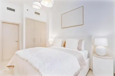 a white bedroom with a bed with a white blanket at Elegant 1BR Apartment with Partial Sea View by EE holiday homes in Dubai
