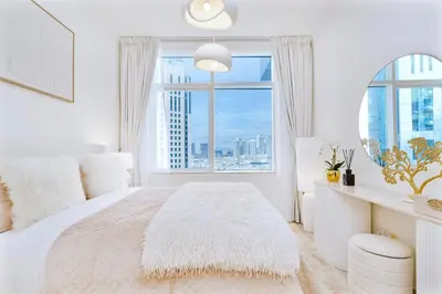 a white bedroom with a large window at Elegant 1BR Apartment with Partial Sea View by EE holiday homes in Dubai