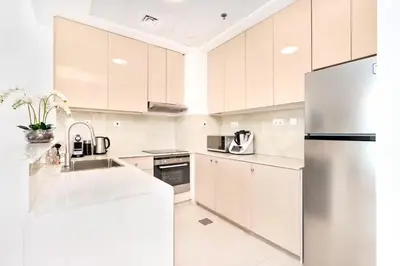 a kitchen with white cabinets and a stainless steel refrigerator at Elegant 1BR Apartment with Partial Sea View by EE holiday homes in Dubai