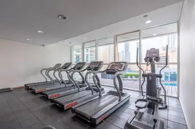 a row of treadmills in a gym with a large window at Elegant 1BR Apartment with Partial Sea View by EE holiday homes in Dubai