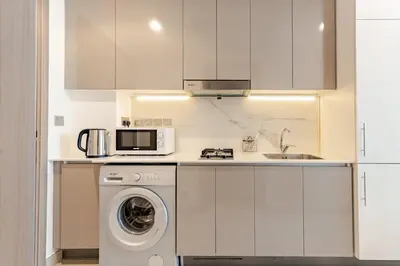 a kitchen with a washing machine and a microwave at Greige & Spacious Studio in Dubai