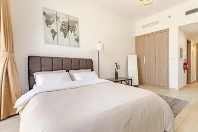 a bedroom with a large white bed with a brown headboard at Greige & Spacious Studio in Dubai