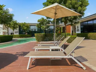 four lounge chairs and an umbrella next to a pool at Golden Stays - Elegant 4BR I Santorini-Style I Sunsets & Comfort in Dubai