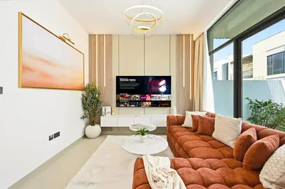 a living room with a couch and a tv at Golden Stays - Elegant 4BR I Santorini-Style I Sunsets & Comfort in Dubai