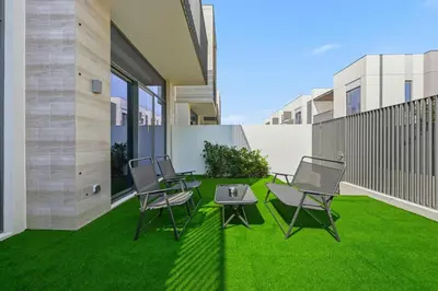 a patio with chairs and a table on the grass at Golden Stays - Elegant 4BR I Santorini-Style I Sunsets & Comfort in Dubai