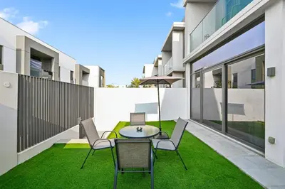 a patio with a table and chairs on the grass at Golden Stays - Stylish 4BR Villa I Garden, Pool & Parking I Global Village in Dubai