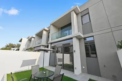 a building with a table and chairs in front of it at Golden Stays - Stylish 4BR Villa I Garden, Pool & Parking I Global Village in Dubai