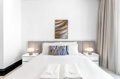 a bedroom with a large white bed with two lamps at Luxury 1BR Terraces Private Jacuzzi Business Bay in Dubai