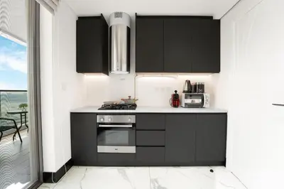a kitchen with black cabinets and a stove at Luxury 1BR Terraces Private Jacuzzi Business Bay in Dubai