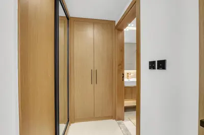 a hallway with wooden cabinets and a mirror at Waves - Comfy and Stylish 1BR with Huge Balcony in Dubai