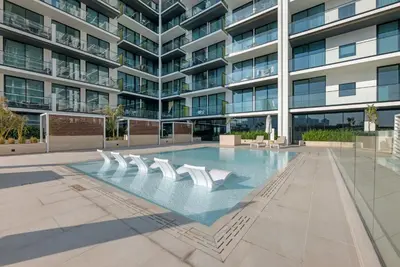 a swimming pool in front of a building at Waves - Comfy and Stylish 1BR with Huge Balcony in Dubai