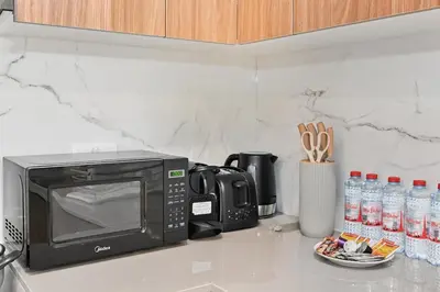 a kitchen counter with a microwave and bottles of water at Golden Stays - Chic 4BR Retreat I Luxe Touches & Serene Views in Dubai