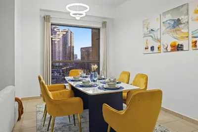 a dining room with a table and chairs and a window at Stylish 3BR JBR l Steps to Beach l Balcony l Sleeps 6 in Dubai