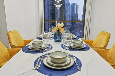 a table with plates and wine glasses and a window at Stylish 3BR JBR l Steps to Beach l Balcony l Sleeps 6 in Dubai