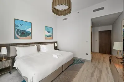 a bedroom with a large white bed and a chandelier at Golden Stays - Palm Views I Luxe 4BR Getaway I Tranquil Charm in Dubai