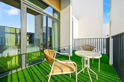 a balcony with a table and chairs on the grass at Golden Stays - Italian Riviera 4BR Villa I Stylish Bliss Living in Dubai