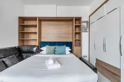 a bedroom with a large bed with black leather furniture at GuestReady - Studio l Close to Metro Station in Dubai