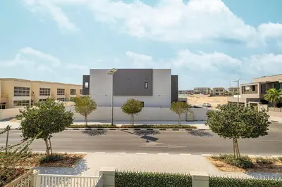 a building with trees in front of a parking lot at Modern 4Bedroom Villa in Al Furjan in Dubai