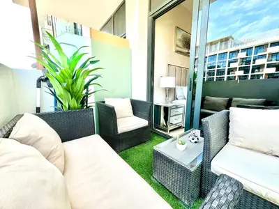 a patio with a couch and chairs on a balcony at Luxury Stay in Meydan - 10min to Downtown in Dubai