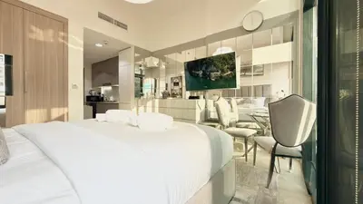 a bedroom with a large white bed and a dining room at Luxury Stay in Meydan - 10min to Downtown in Dubai