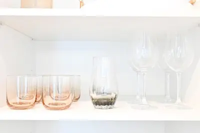 a row of wine glasses sitting on a shelf at Golden Stays - Luxe 1BR Retreat I Cinema Access & Elegant Stay in Dubai