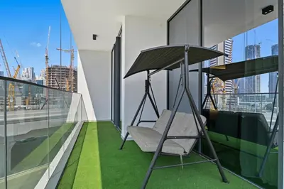 a balcony with a chair and an umbrella on a building at Golden Stays - Luxury 1BR Apartment I Cinema Access I Pool & Gym in Dubai